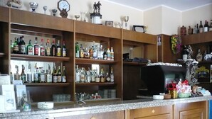 A bar area with wooden cabinets and shelves stocked with various bottles and glasses. - Albergo Regina (Bognanco)