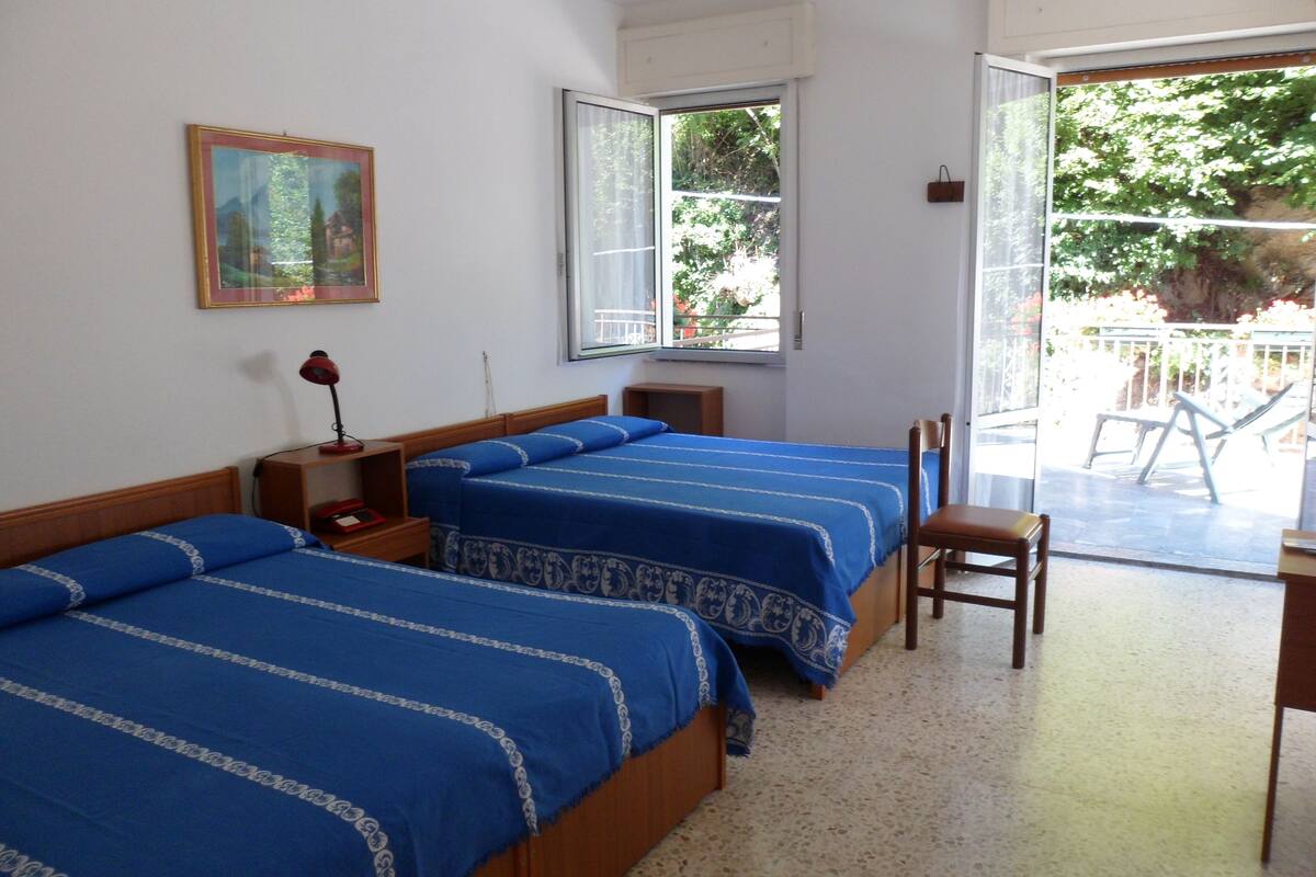 A hotel room with two beds, a window, a chair, and a desk.