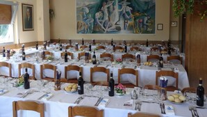 A banquet hall with multiple tables set for a formal event, featuring white tablecloths, wine bottles, and floral centerpieces. - Albergo Regina (Bognanco)
