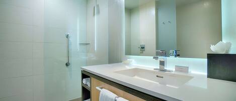 A modern bathroom with a large mirror, a sink, and a shower area.