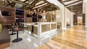 Un área de bar moderna con mostrador, asientos y una estructura de techo de madera.