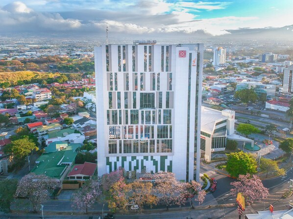Un edificio de gran altura con diseño moderno, destacando un amplio frente de vidrio y un logotipo prominente en la parte superior.
