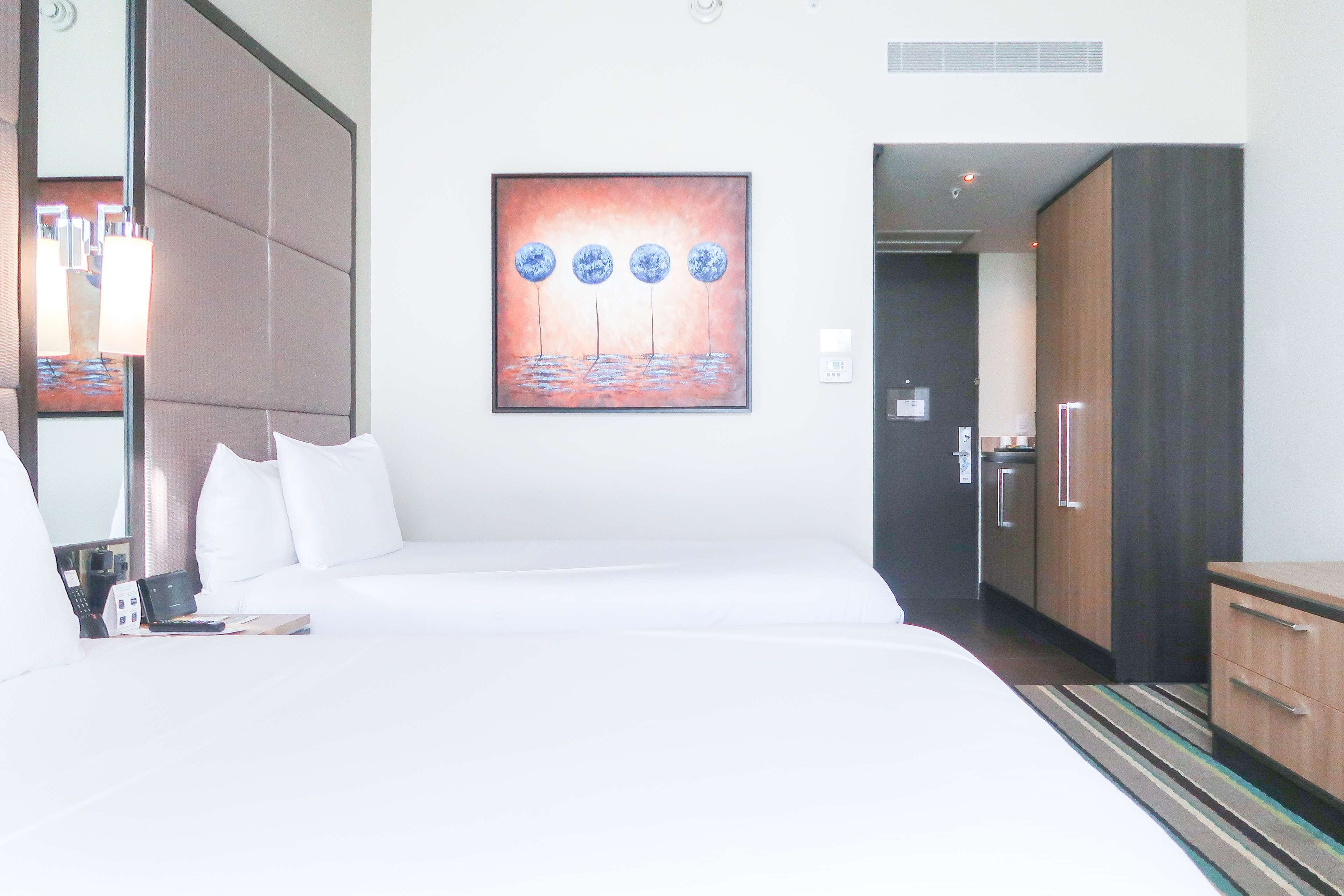 Quarto de hotel com uma cama grande, um quadro na parede, um guarda-roupa e uma mesa.