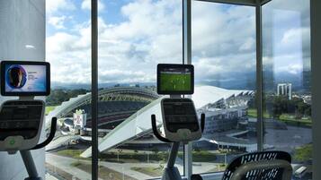 A gym with two treadmills, large windows with a view of a stadium and surrounding buildings.