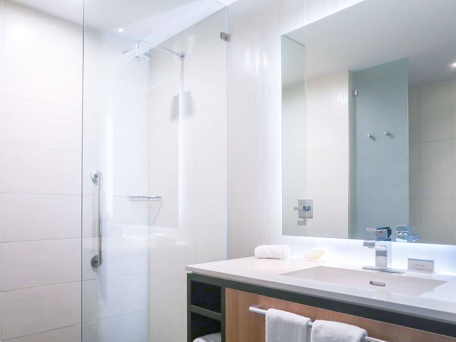 A modern bathroom with a glass shower enclosure, a large mirror, and a white sink.