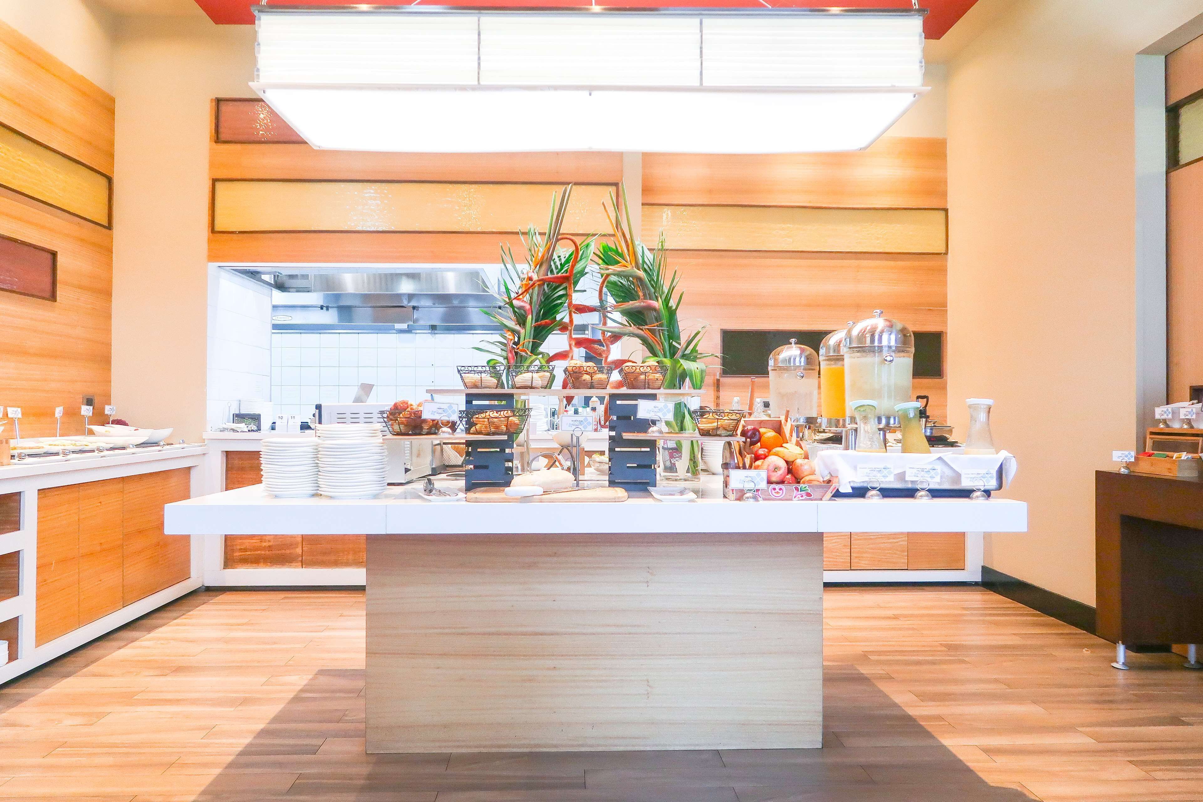 Une cuisine moderne dotée d’un îlot central, de lambris en bois et de divers distributeurs de boissons et d’aliments.