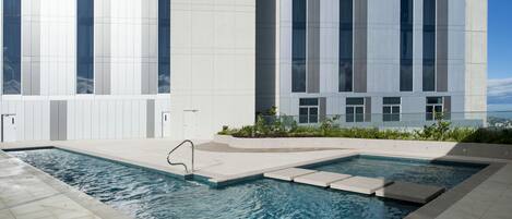 A modern building with a swimming pool and a clear sky.