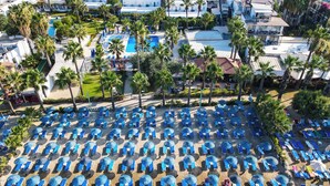 An aerial view of a resort with multiple pools, sun loungers, and palm trees. - Nagi Beach Hotel (Bodrum)