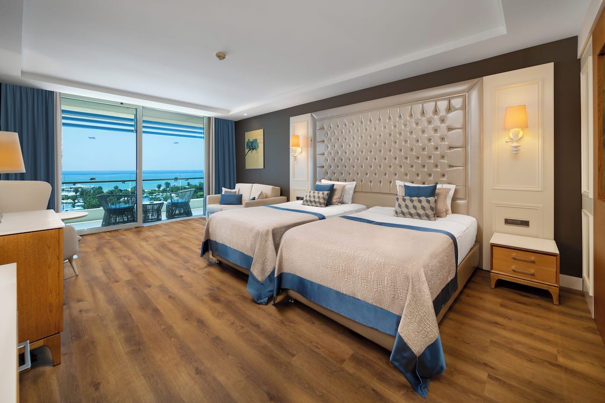 Ein Hotelzimmer mit einem großen Bett, einem Schreibtisch und Blick auf den Ozean.
