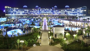 A large hotel with multiple swimming pools, a central walkway, and outdoor seating areas. - Sueno Hotels Deluxe Belek - All Inclusive (Serik)