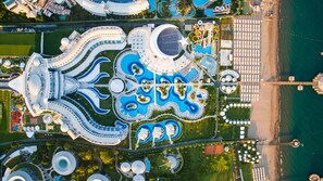 An aerial view of a large, modern complex with multiple buildings, a central water feature, and a beach area. - Sueno Hotels Deluxe Belek - All Inclusive (Serik)