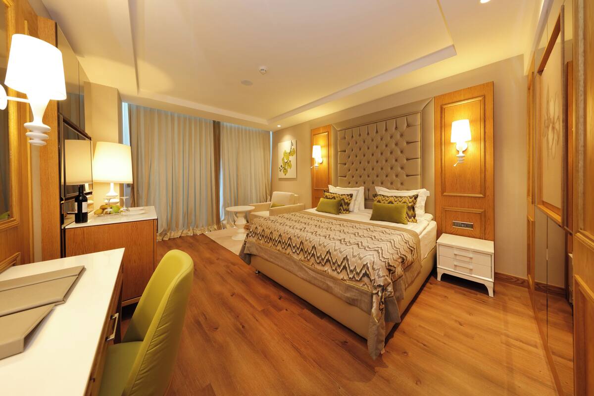 Ein Hotelzimmer mit einem großen Bett, Nachttischen, einem Schreibtisch und einem Sessel.