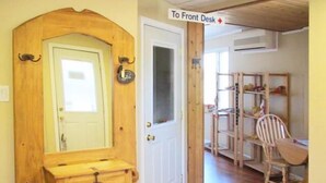 A wooden door with a mirror and a small drawer, leading to a room with a wooden desk, chair, and shelves.