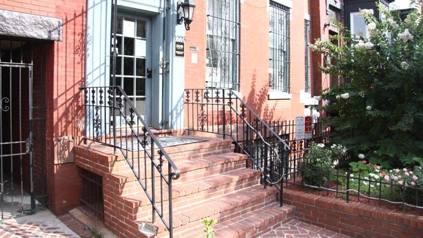 A brick building with a red facade, a white door, and a black metal staircase leading to the entrance. - Duo Housing Hostel (Washington)