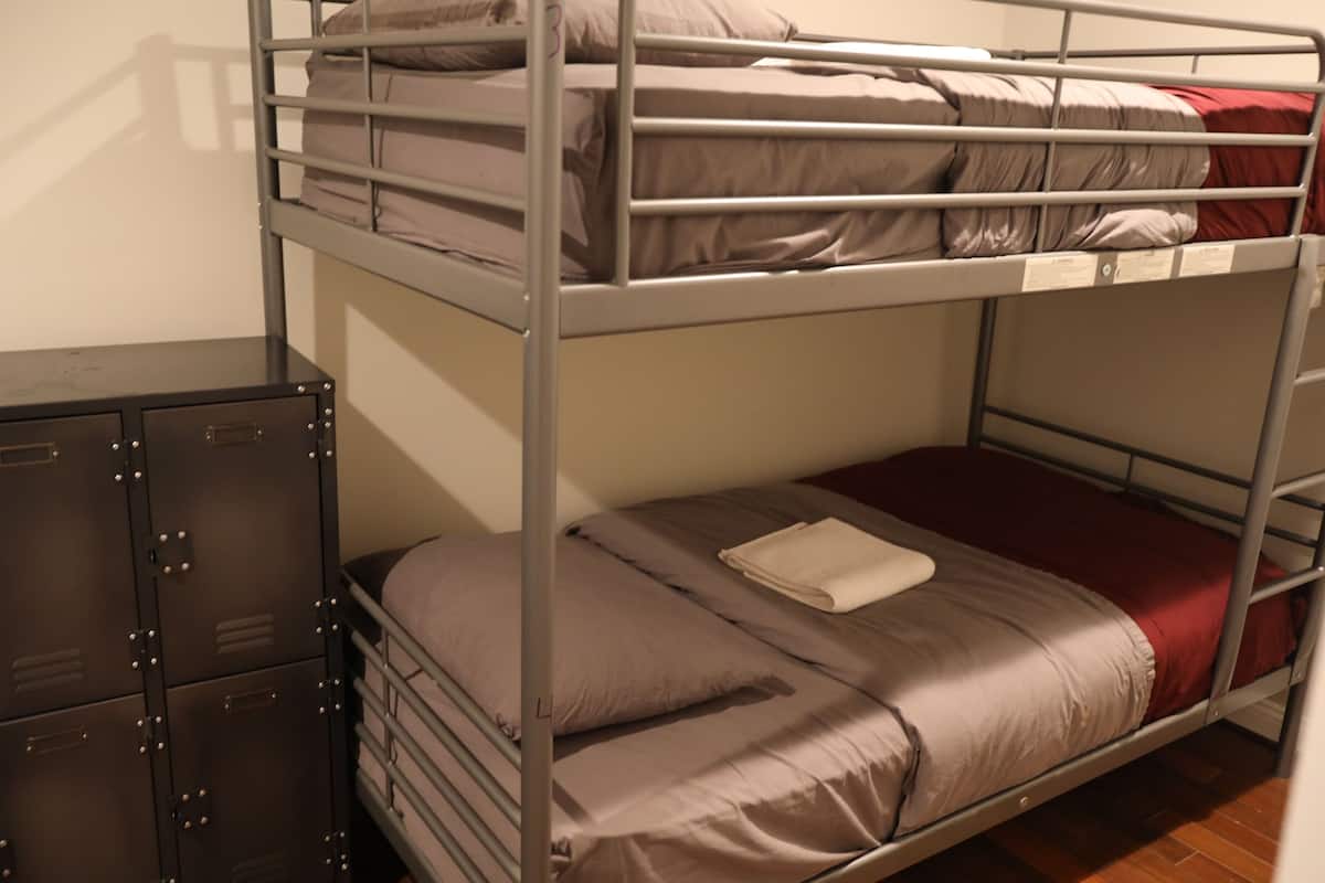 A bunk bed with a metal frame, a small desk with drawers, and a set of cabinets.