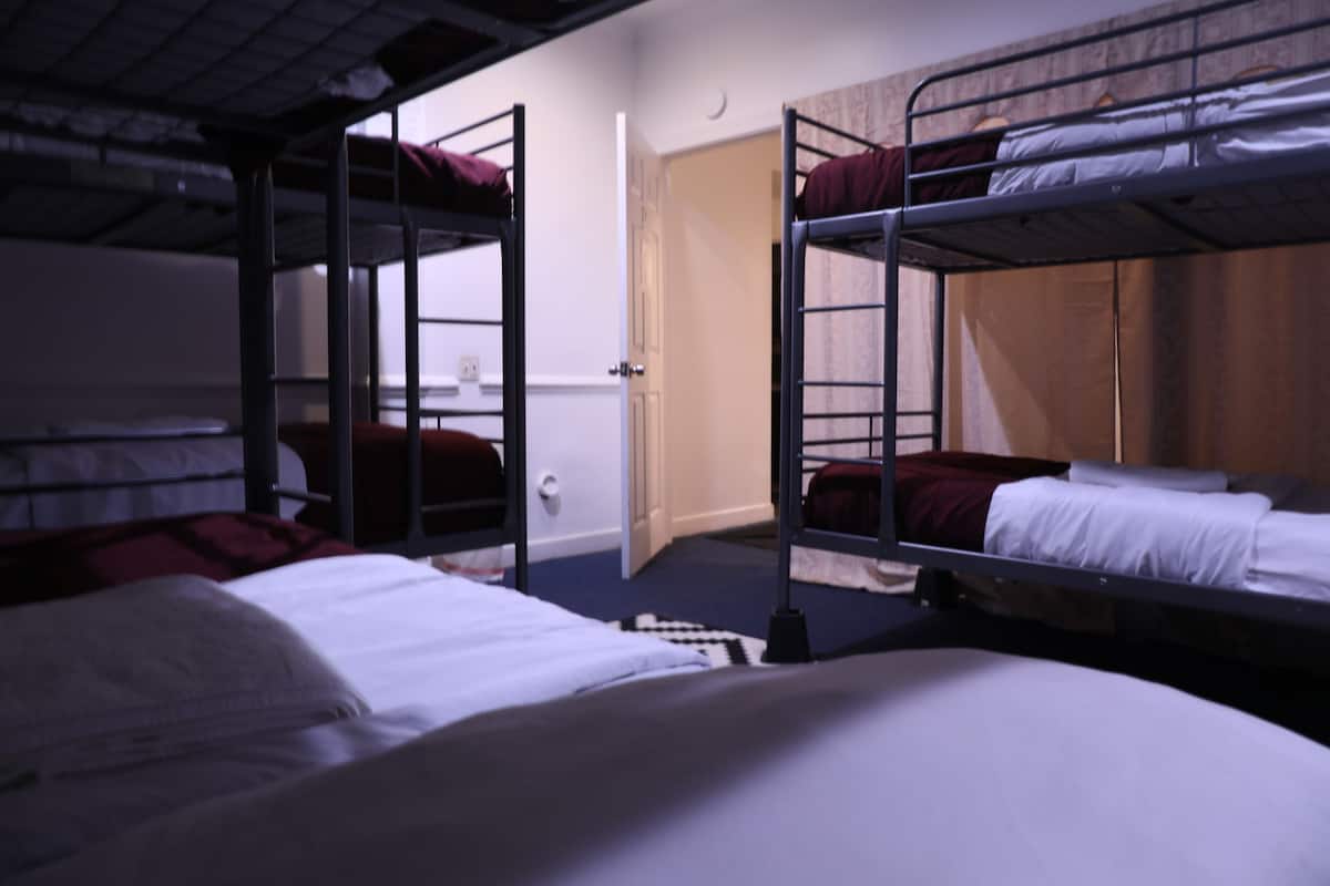 A dormitory room with bunk beds, a door, and a window.