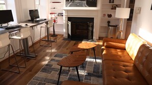 A modern living room with a sofa, a coffee table, a fireplace, and a desk with a computer. - Duo Housing Hostel (Washington)