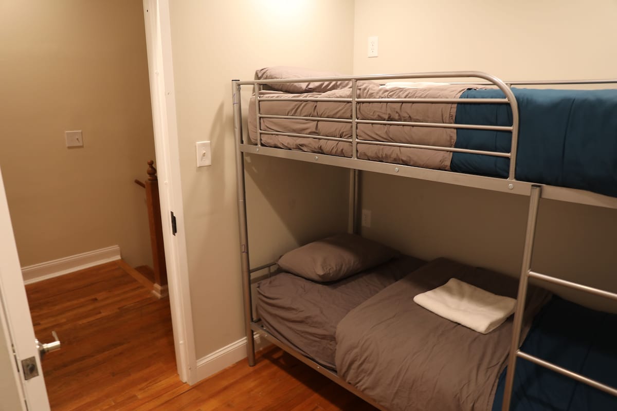A bunk bed room with a wooden floor and a white door.