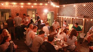 An outdoor dining area with brick walls and string lights, surrounded by a wooden fence. - Duo Housing Hostel (Washington)