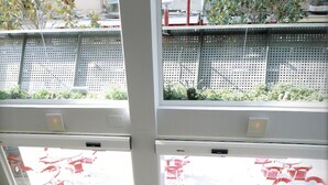 A reception area with a desk, chairs, and a view of the outdoor seating area through large windows. - Evenia President Hotel (Salou)