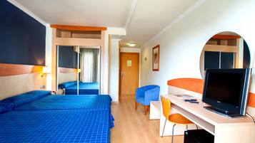 Una habitación de hotel con dos camas, un escritorio con computadora y televisión.