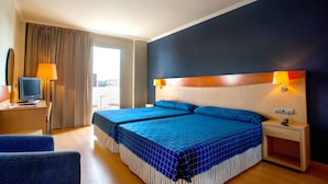 A hotel room with two beds, a desk with a television, and a window with curtains. - Evenia President Hotel (Salou)