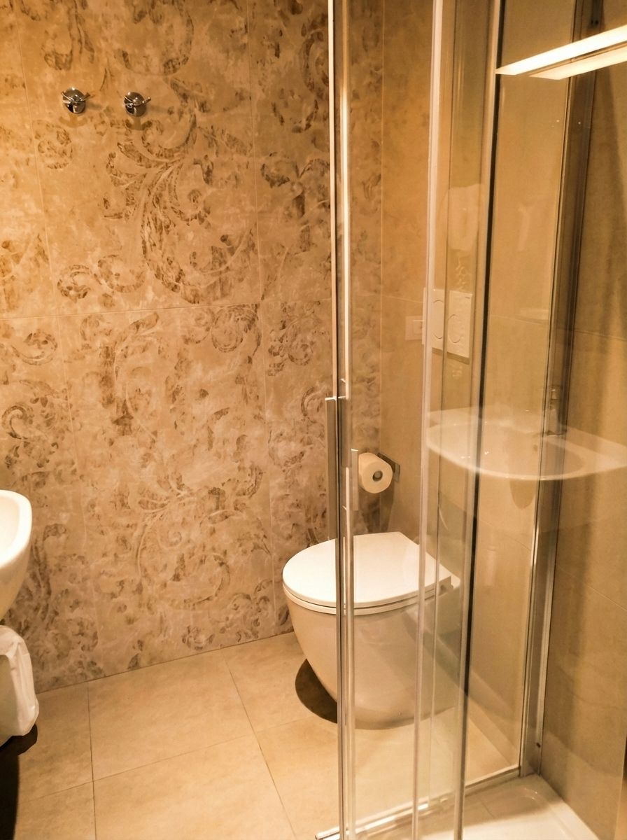 A bathroom with a marble wall, a toilet, and a glass shower enclosure.