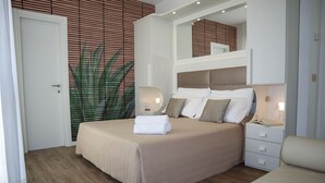 A neatly arranged bedroom with a bed, bedside tables, and a mirror. - Hotel Columbia & Ninfea (Jesolo)