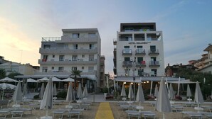 A hotel with multiple floors, outdoor seating with umbrellas, and a yellow pathway leading to the entrance. - Hotel Columbia & Ninfea (Jesolo)