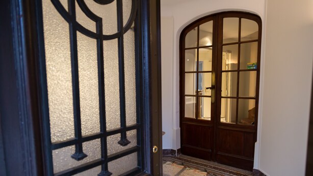 A wooden door with a glass panel and a metal grille. - Hôtel Le Home (Vincennes)