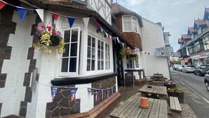 Un pub tradicional llamado 'The Castle' con fachada de estilo Tudor, mesas al aire libre y un letrero que indica estacionamiento cercano.
