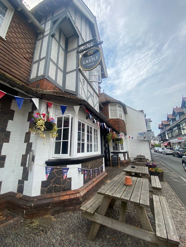 A traditional pub named 'The Castle' with a Tudor-style facade, outdoor seating, and a sign indicating nearby parking. - The Castle Inn (Minehead)
