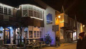 Un pub tradicional con terraza, un árbol de Navidad y un cartel que indica lugares cercanos.