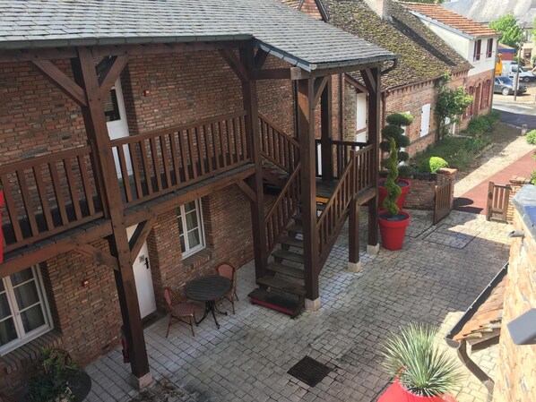 A two-story building with a wooden balcony, brick walls, and a tiled roof.