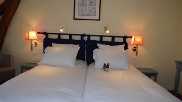 A double bed with white linens, two bedside tables with lamps, and a framed artwork above the bed.