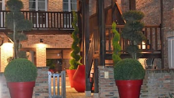 A brick building with a wooden balcony and red potted plants.