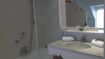 Une salle de bain moderne avec une baignoire, une douche, un lavabo et un miroir.