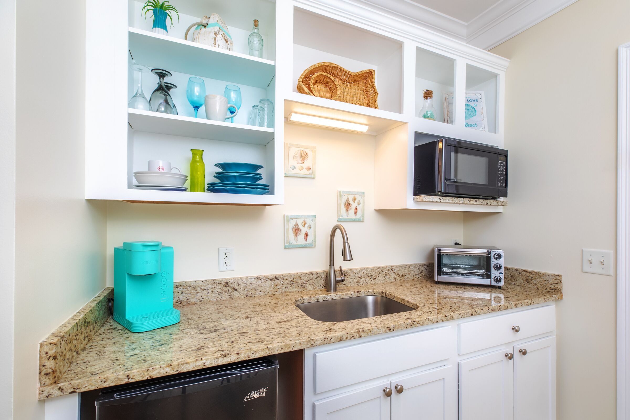 A kitchen with white cabinets, a granite countertop, a sink, a toaster, a microwave, and a dishwasher.