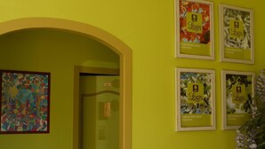 Un couloir avec un mur vert, une œuvre d’art colorée encadrée et quatre panneaux « Logis » encadrés.