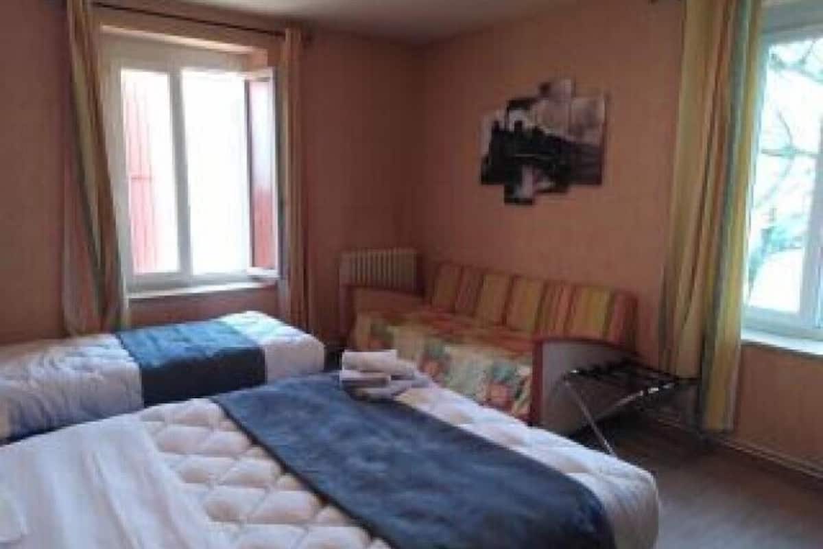 Une chambre avec deux lits, un radiateur et une fenêtre avec des rideaux.