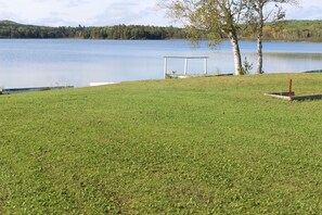 A grassy area with a white structure near a lake.