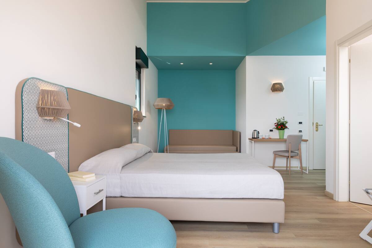 A modern hotel room with a large bed, a desk, and a chair.