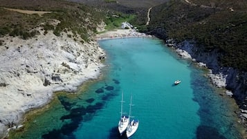 A coastal area with clear turquoise waters, rocky shores, and a boat anchored near the shore.