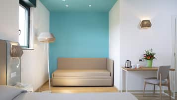 Una habitación moderna con un sofá, un escritorio con una silla, una lámpara y una mesita con una planta.