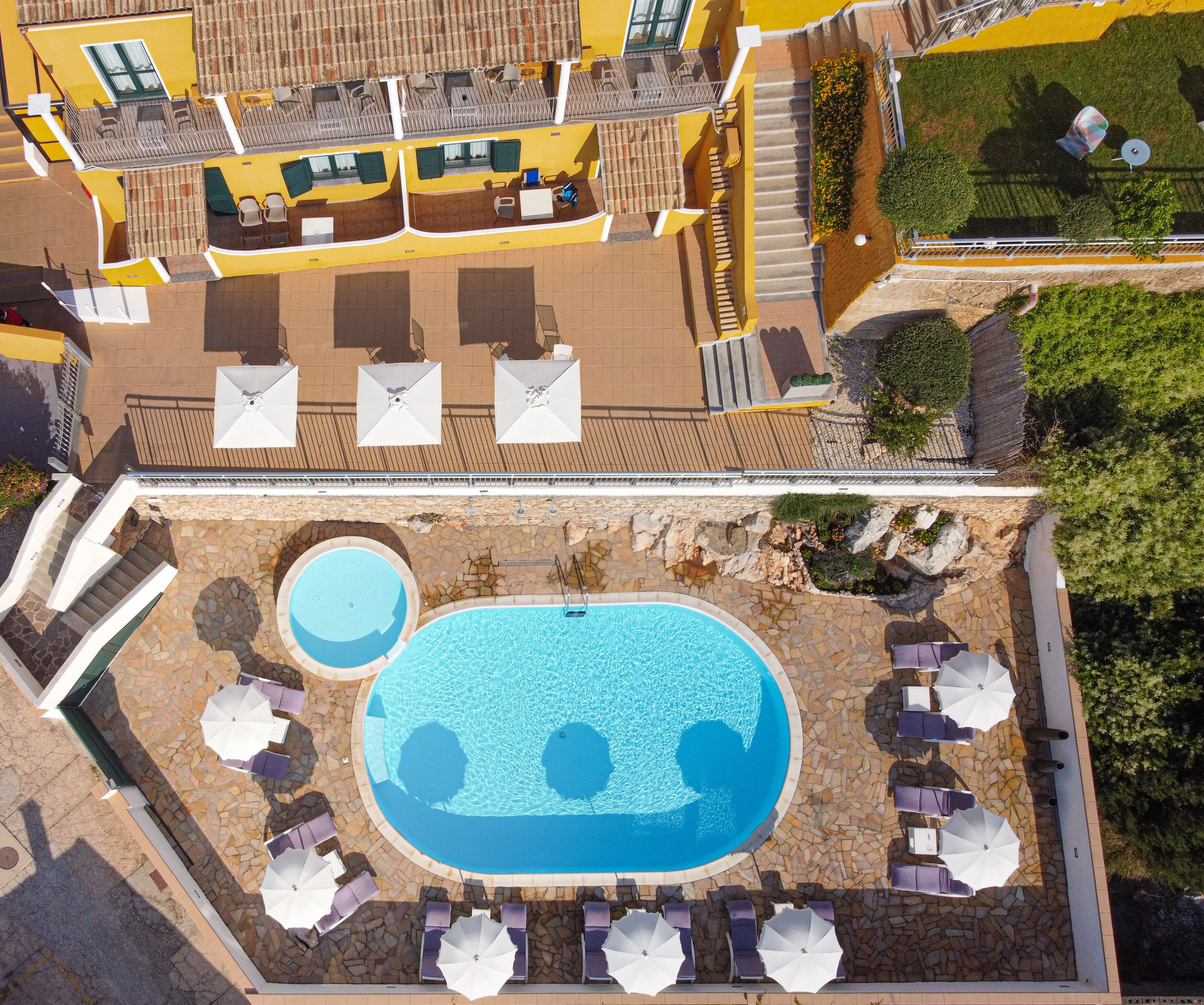 Et tagområde med pool, liggestole og parasoller, samt en mindre pool og en trappe op til en øvre dæk med siddepladser.