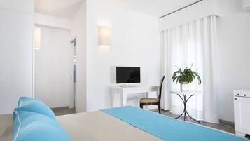 Una habitación de hotel con una cama, un escritorio con televisor, una silla, una planta y un armario.