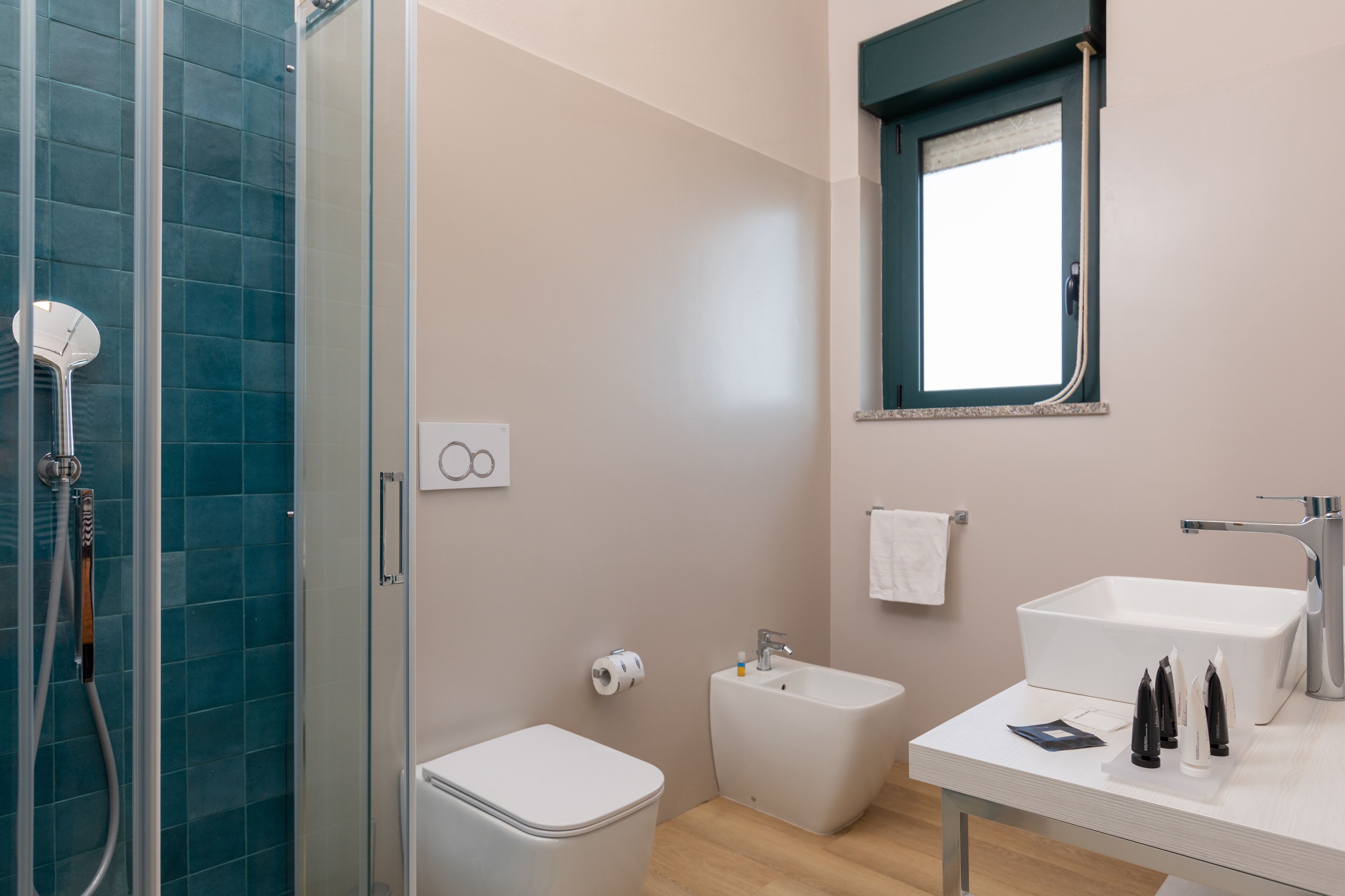 Un baño moderno con cabina de ducha de vidrio, un bidé, un inodoro y un lavabo con espejo.