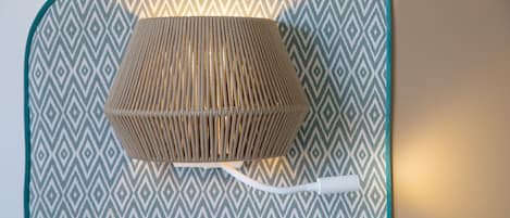 A woven ottoman with a white cord on a patterned fabric backdrop.