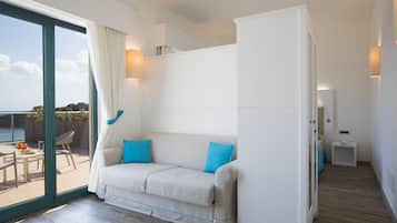 A modern room with a sofa, a small table, and a view of the sea.