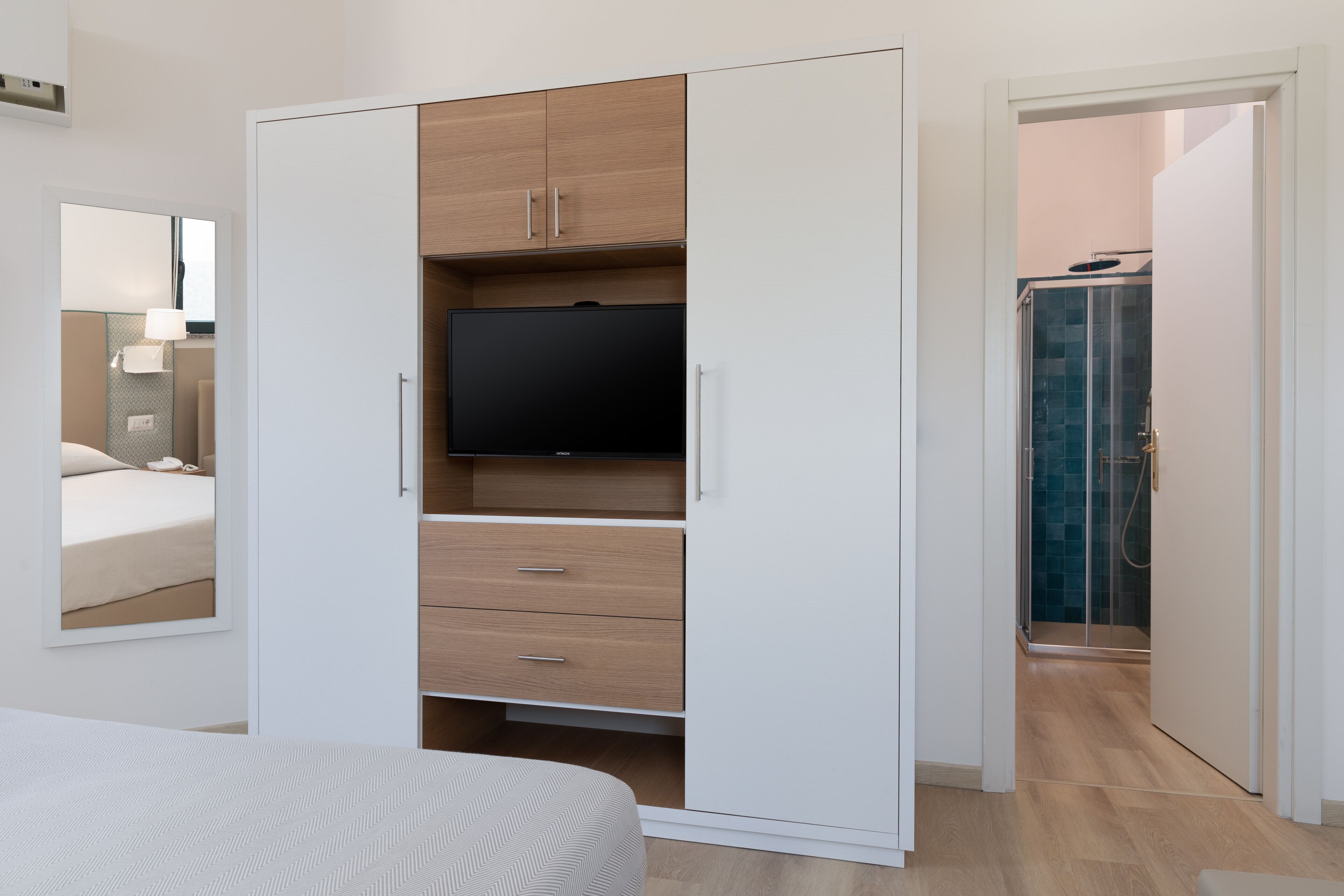 Ein Schlafzimmer mit Bett, einem Schrank mit Fernseher und einer Duschkabine.